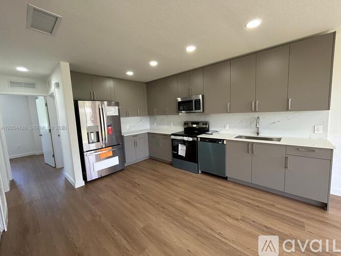 A kitchen with wooden floors and a refrigerator with a water dispenser.