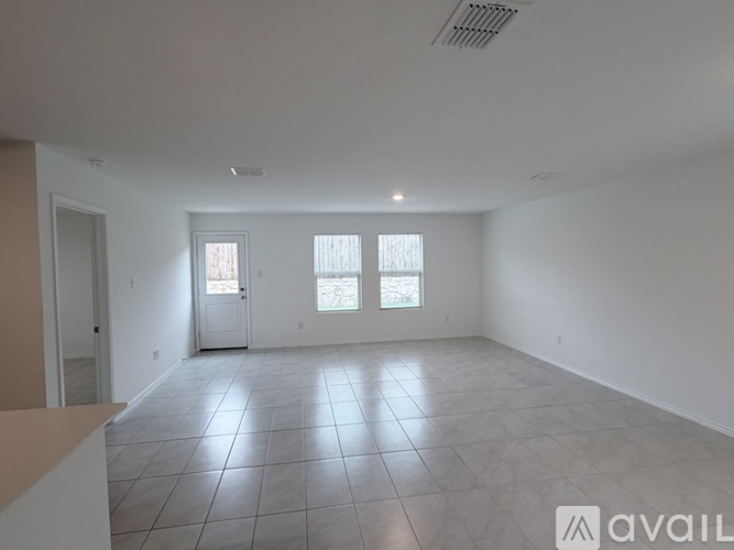 A spacious room with tile flooring and two windows.