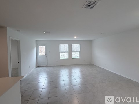A spacious room with tile flooring and two windows.
