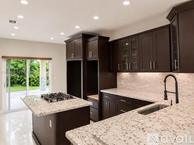 A kitchen with brown cabinets and a marble countertop.