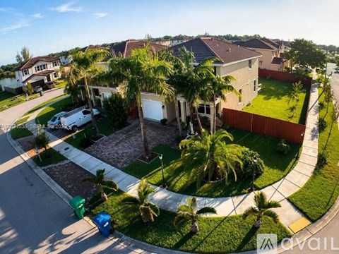 A house with a driveway and palm trees in front.