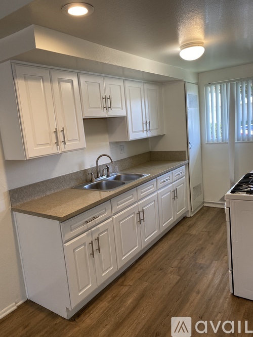 A kitchen with white cabinets and a wooden floor.