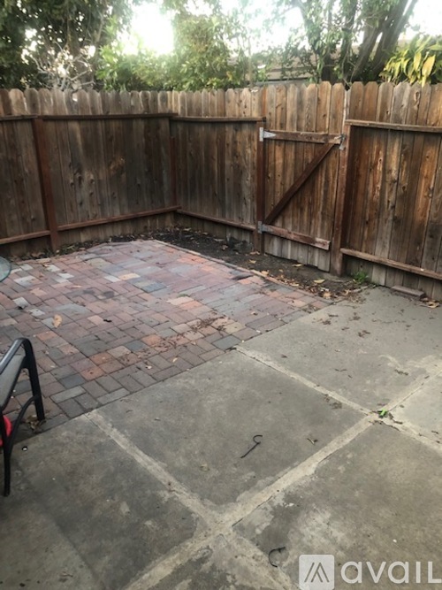 A backyard with a wooden fence and a brick patio.
