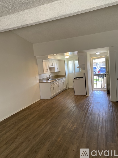 A kitchen with white cabinets and a wooden floor.