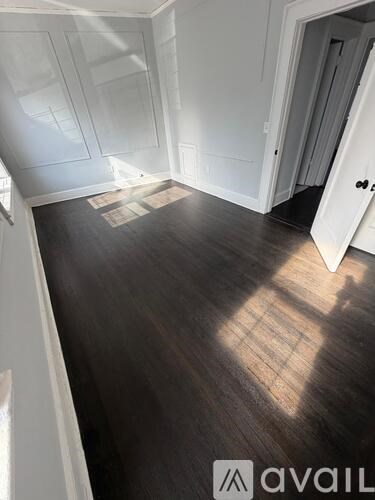A room with wooden flooring and white walls.