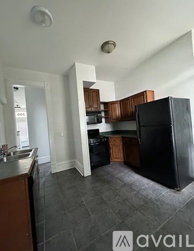 A kitchen with a black fridge and wooden cabinets.
