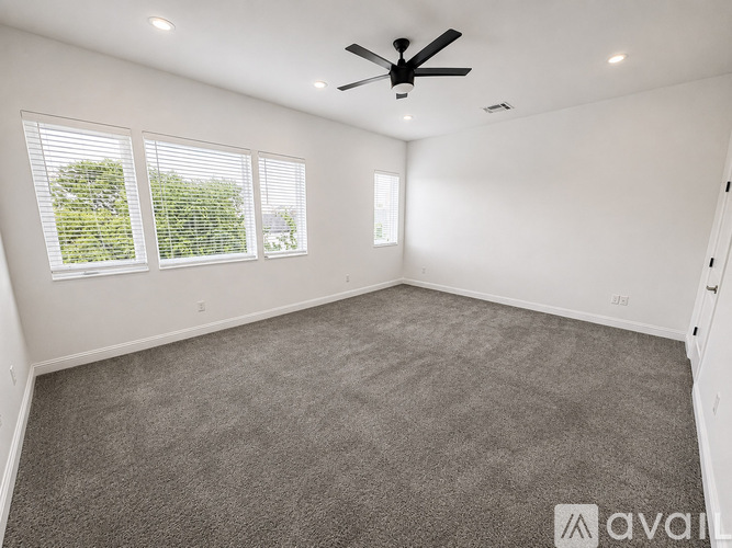 A spacious room with a ceiling fan and carpeted floor.
