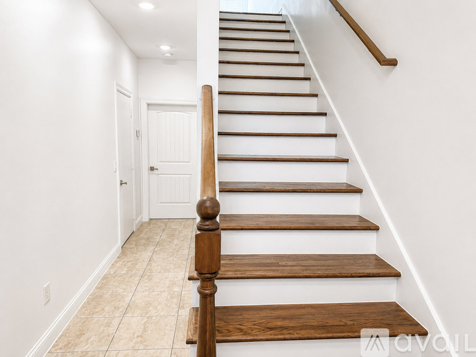 A wooden staircase with a white wall on one side and a white door on the other.