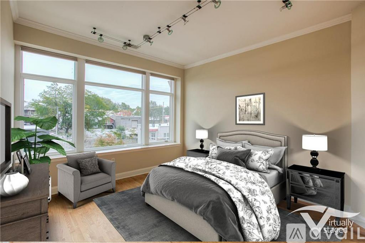 A bedroom with a large bed, a chair, and a window overlooking a cityscape.