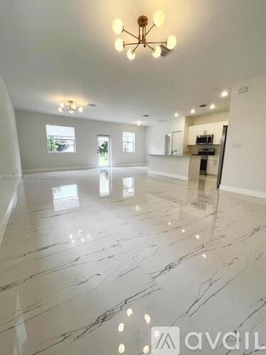 A spacious room with marble flooring and a chandelier.