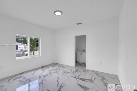 A spacious room with marble flooring and a view of a street through a window.
