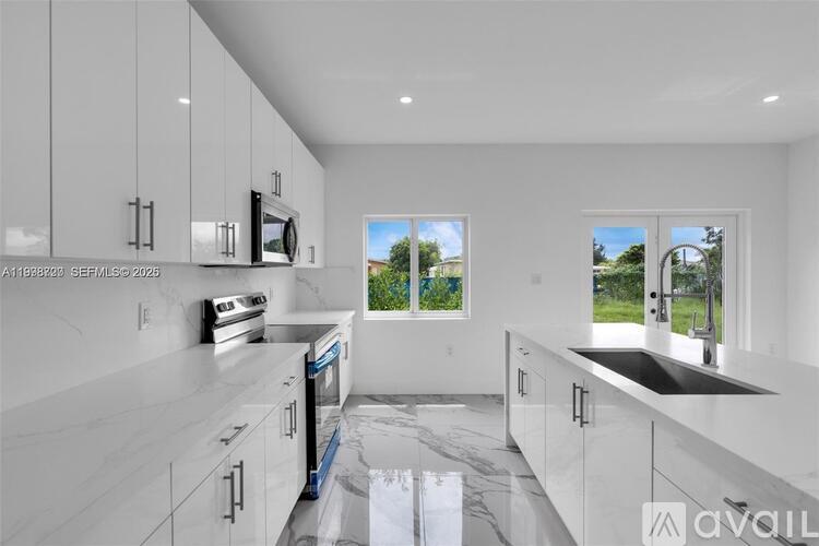A modern kitchen with white cabinets and a marble countertop.