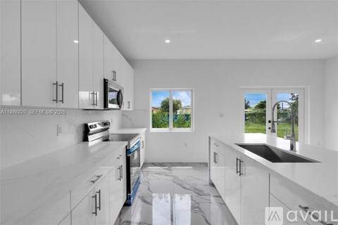 A modern kitchen with white cabinets and a marble countertop.