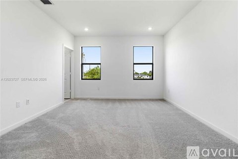 A large empty room with two windows and a door.