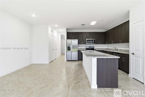 A spacious kitchen with dark wood cabinets and a white island.
