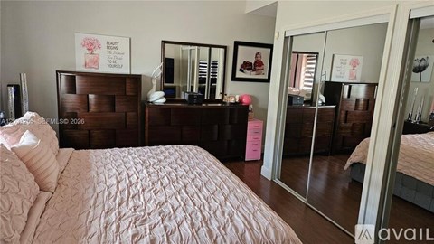 A bedroom with a large bed and a vanity with a mirror.