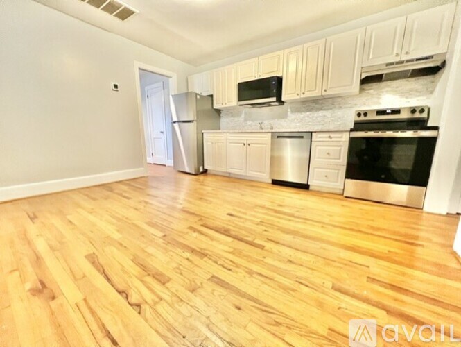 A kitchen with wooden floors and white cabinets.