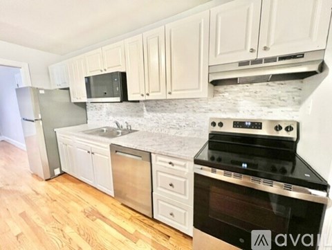 A kitchen with a black stove top oven and white cabinets.