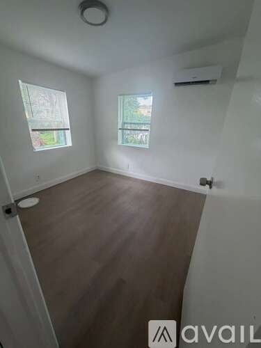 A room with wooden floors and two windows.