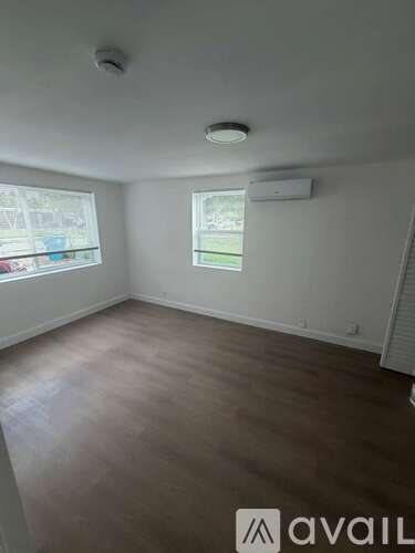 A room with wooden flooring and a window overlooking a parking lot.