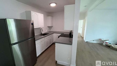 A kitchen with white cabinets and a stainless steel refrigerator.