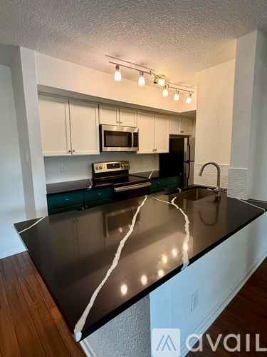 A kitchen with a black countertop and white cabinets.
