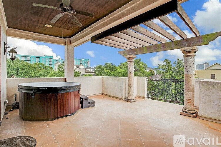 A patio with a hot tub and a ceiling fan.