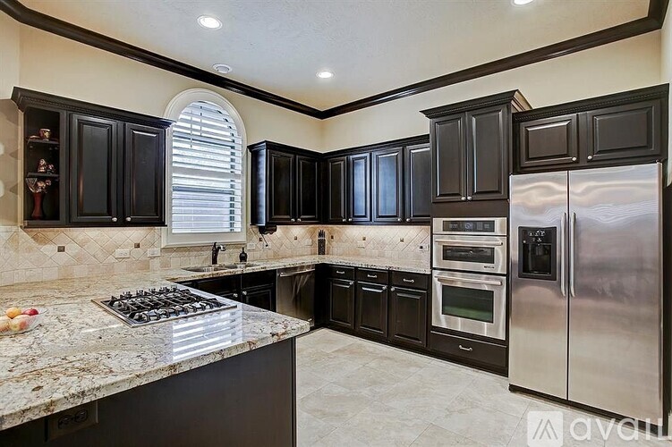 A kitchen with black cabinets and a granite countertop.