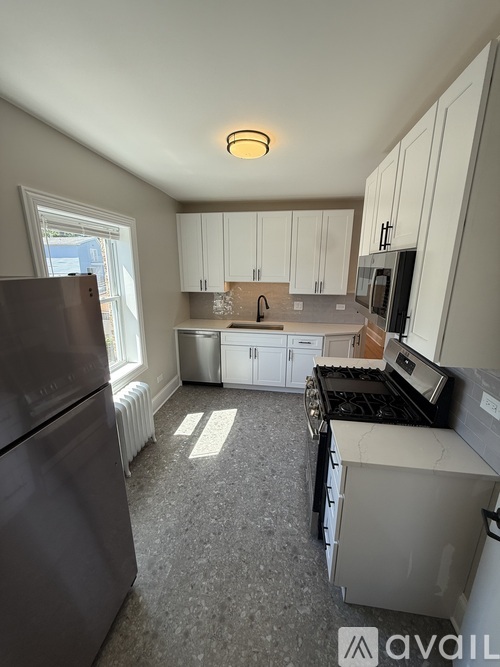 A kitchen with a black fridge and white cabinets.