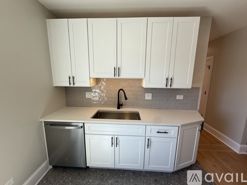 A kitchen with white cabinets and a stainless steel dishwasher.