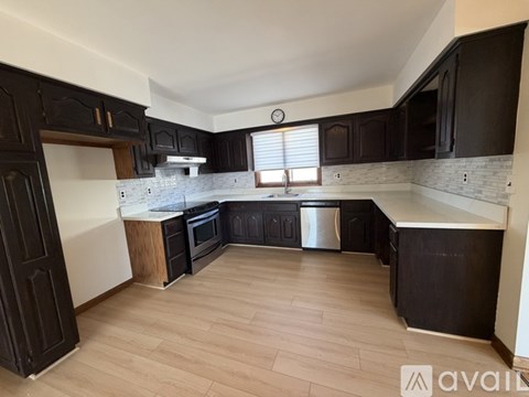 A kitchen with black cabinets and wooden floors is available for rent.