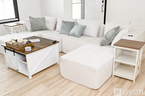 A white living room with a white sofa and a white ottoman.