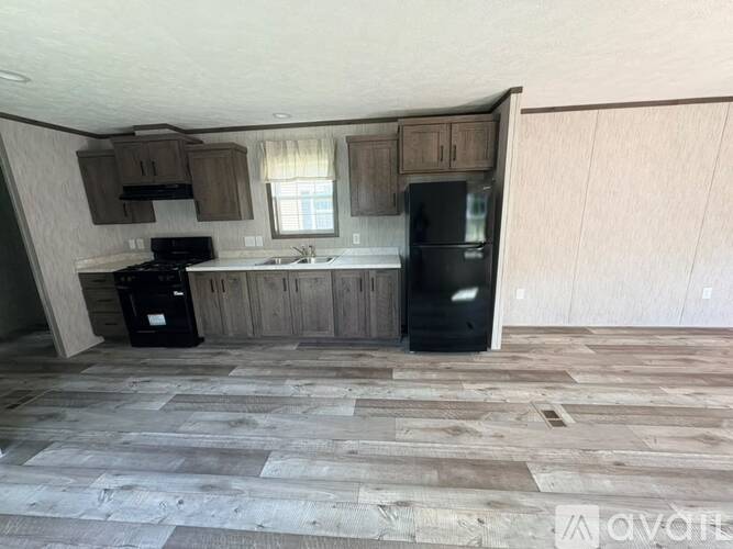A kitchen with wooden cabinets and a black fridge.
