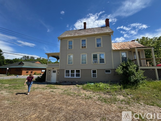 A woman is standing in front of a two-story house.