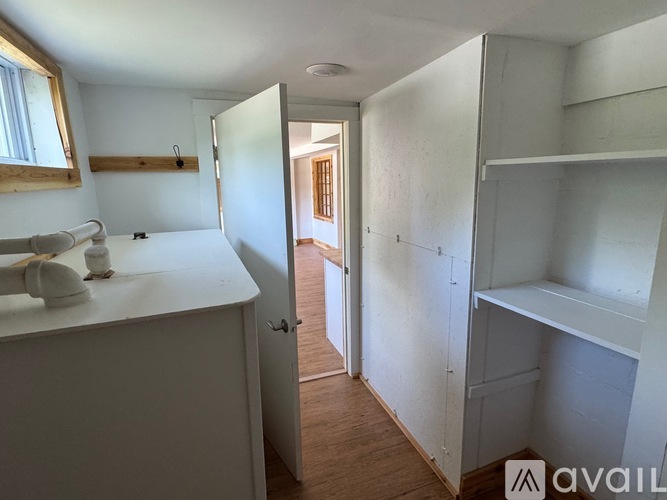 A white kitchen with a sink and a doorway leading to another room.