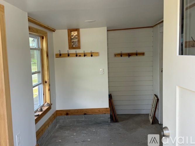 A room with a window and a wall with wooden planks.