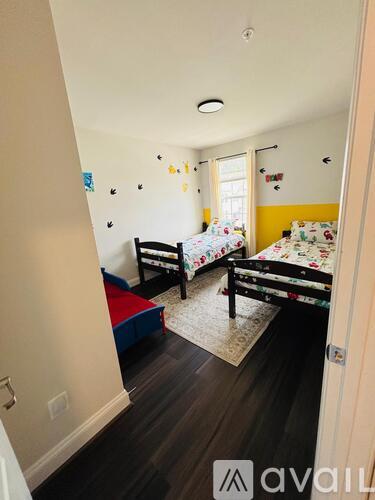 A bedroom with two beds and a rug on the floor.