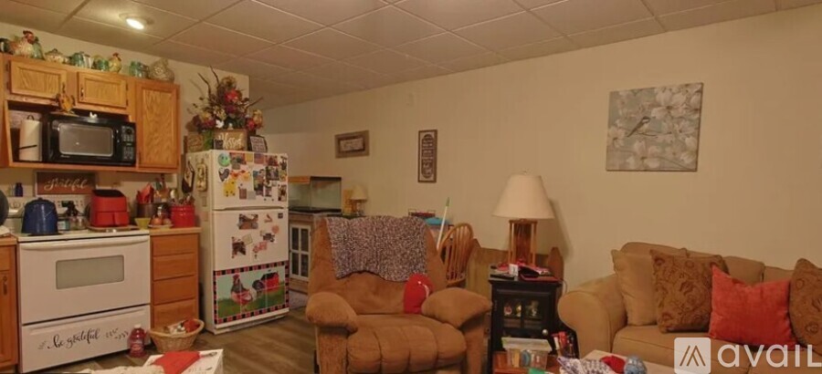 A kitchen with a fridge covered in magnets and a couch with pillows.