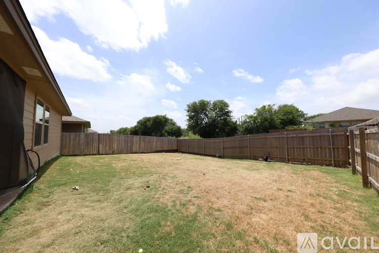 A backyard with a wooden fence and a grassy area.