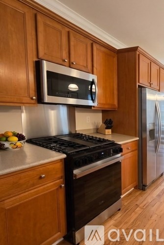 A kitchen with wooden cabinets and a stainless steel refrigerator.