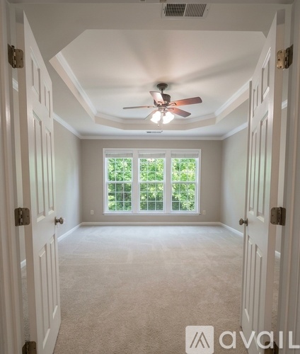 A room with a ceiling fan and a window with a view of trees.
