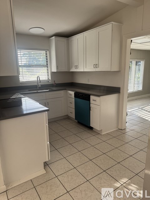 A kitchen with white cabinets and a black countertop.
