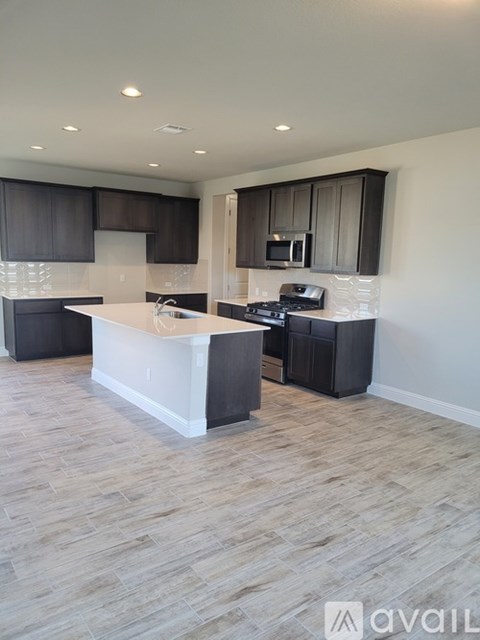 A kitchen with a white island and dark brown cabinets.