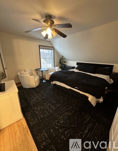 A bedroom with a black bedspread and a ceiling fan.