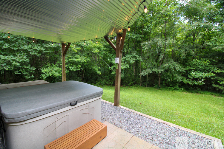 A hot tub is on a patio with a wood deck and a roof.