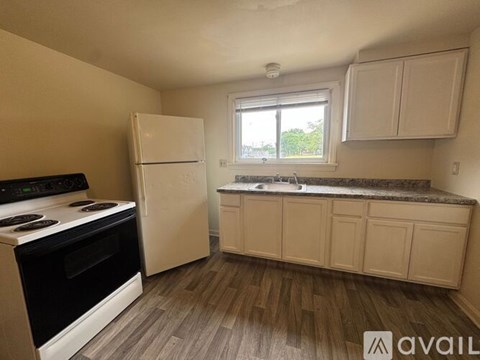 A kitchen with a stove, refrigerator, and cabinets.