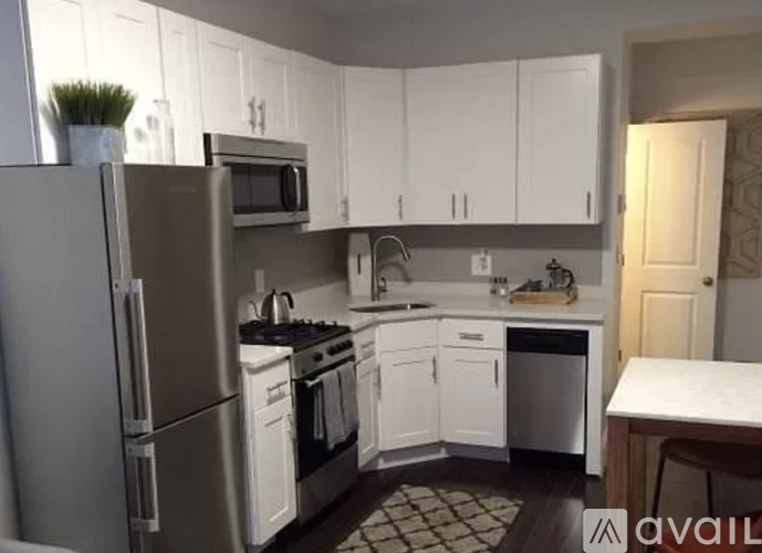 A kitchen with white cabinets and a stainless steel refrigerator.