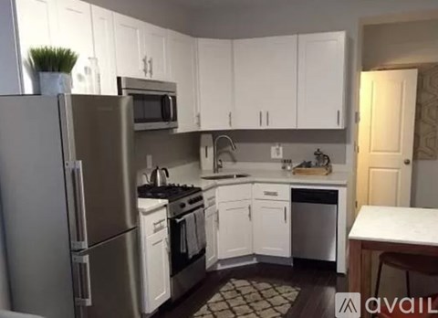 A kitchen with white cabinets and a stainless steel refrigerator.