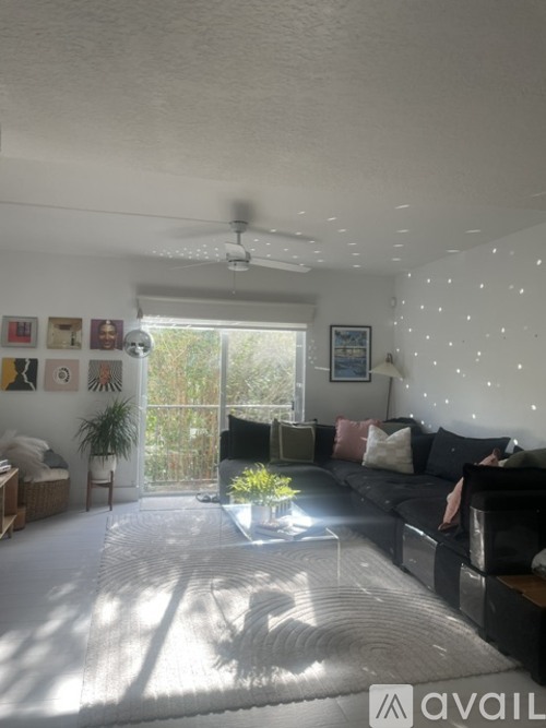 A living room with a black couch and a white ceiling fan.