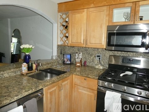 A kitchen with a granite counter top and wooden cabinets.